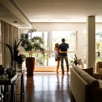 a man and woman standing in a room with a window