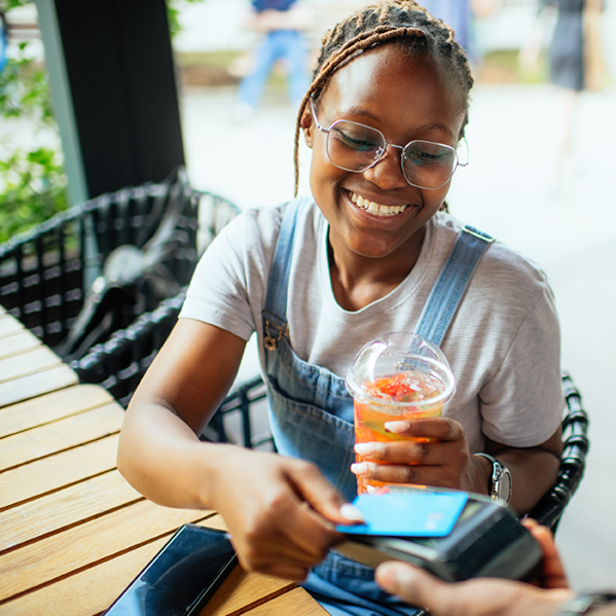a woman smiling as she uses a credit card