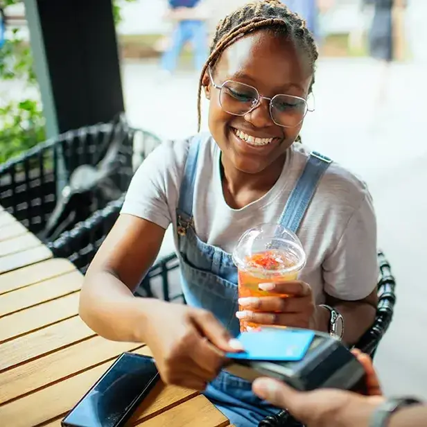a woman smiling as she uses a credit card
