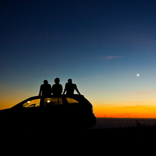 silhouette of people on a car viewing the sunset