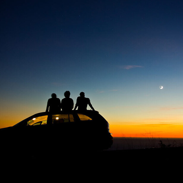 silhouette of people on a car viewing the sunset
