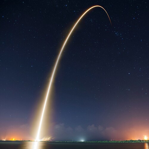 arcing rocket launch trail at night