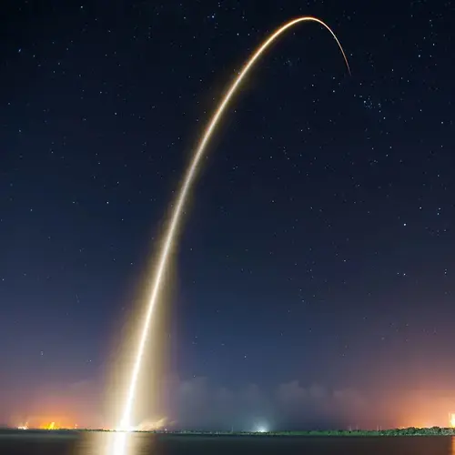 arcing rocket launch trail at night