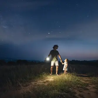 a man and child holding hands with a flashlight