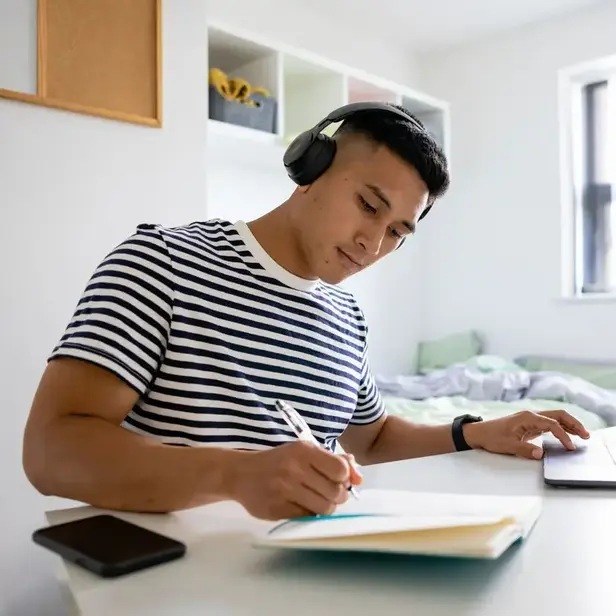 a man wearing headphones writing on a notebook