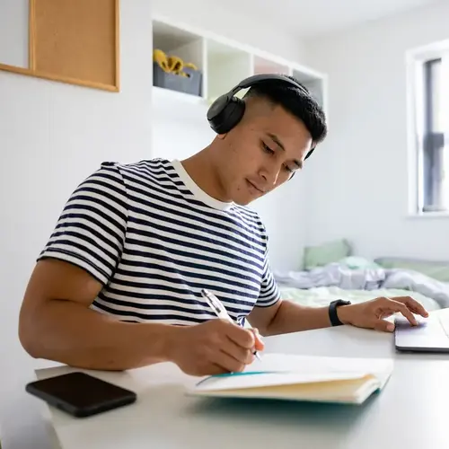 a man wearing headphones writing on a notebook