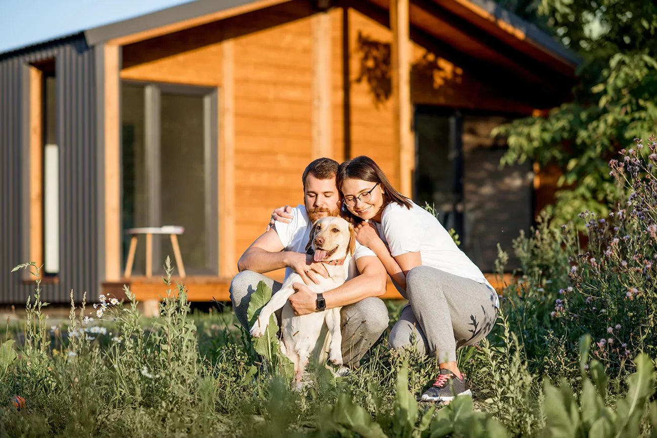 a man and woman with a dog in front of a house