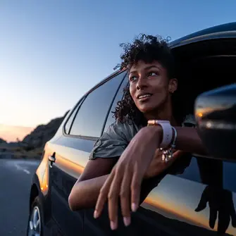 Woman leaning out of car during sunset