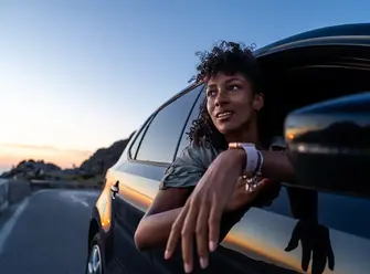 Woman leaning out of car during sunset