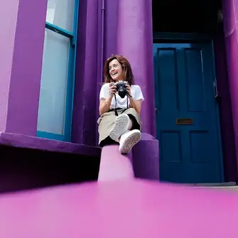 a woman sitting on a ledge holding a camera
