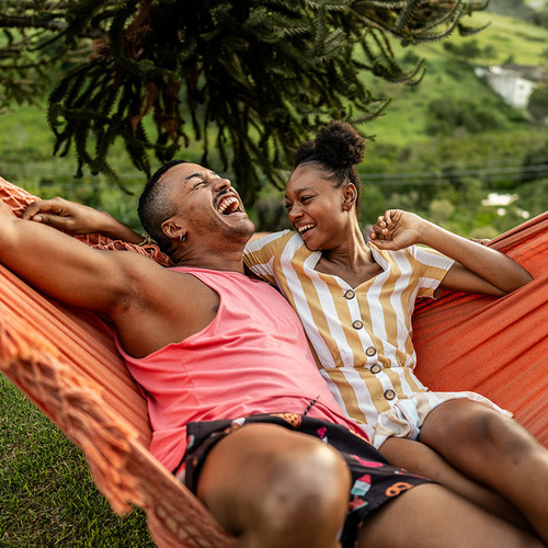LGBTQIA+ friends lying on hammock on house yard