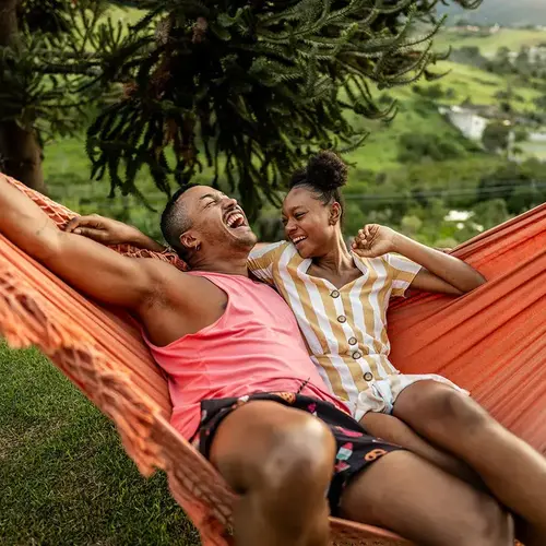 LGBTQIA+ friends lying on hammock on house yard