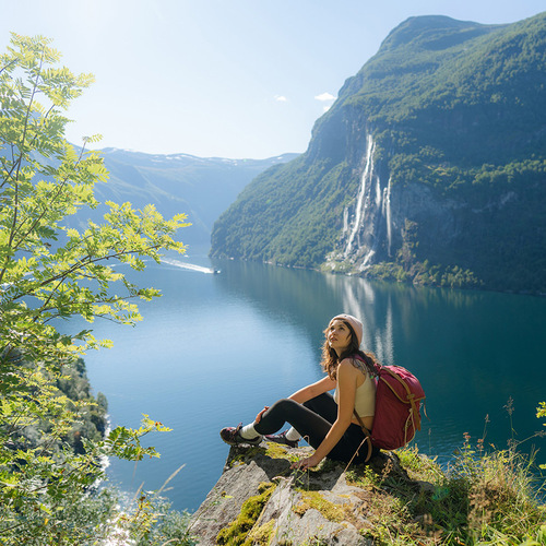 Woman sitting on the background of the Geirangerfjord and Seven Sisters Waterfall
