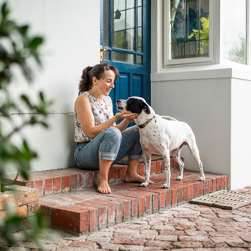 a woman sitting on steps petting a dog