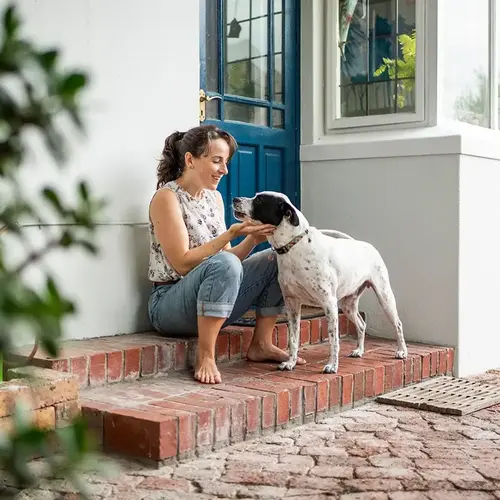 a woman sitting on steps petting a dog