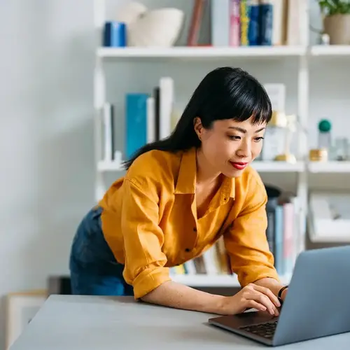 a woman leaning on a desk using a laptop