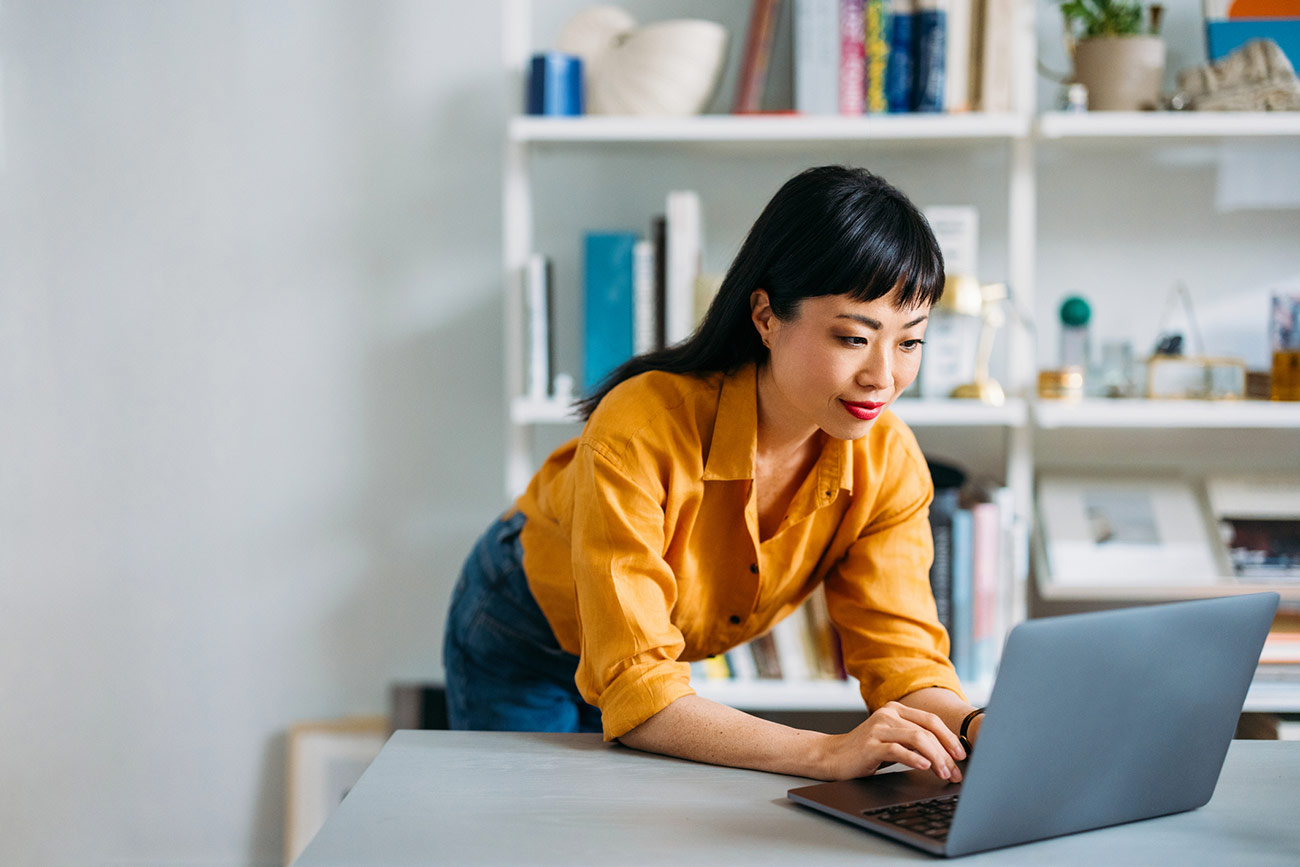 a woman leaning on a desk using a laptop