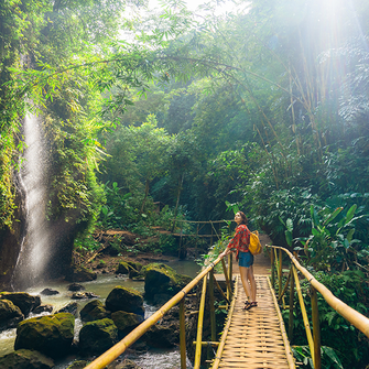 a woman standing on a bridge over a stream
