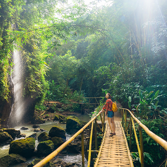a woman standing on a bridge over a stream